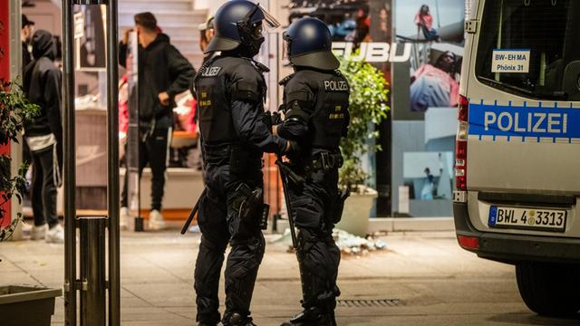 Zwei Polizisten stehen nach den Randalen in der Stuttgarter Innenstadt neben einem Einsatzwagen auf der Königstraße.