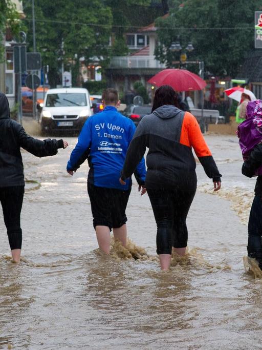 Passanten gehen am 26.07.2017 in Bad Harzburg (Niedersachsen) durch Wasser einer überfluteten Straße. Dauerregen hat im südlichen Niedersachsen in einigen Orten zu Überschwemmungen geführt.