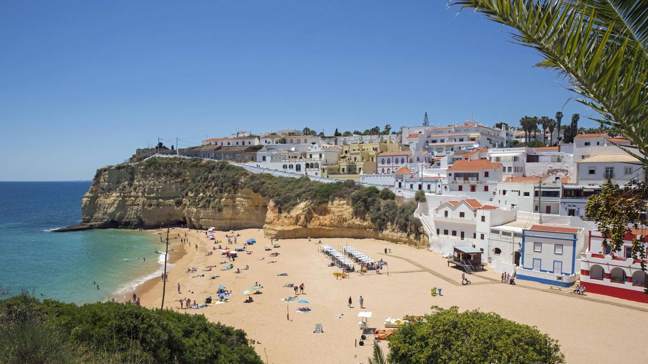 Blick auf den Strand Praia de Carvoeiro an der Algave in Portugal. Im Hintergrund sind zahlreiche nah am Strand liegenden Hotels zu sehen.