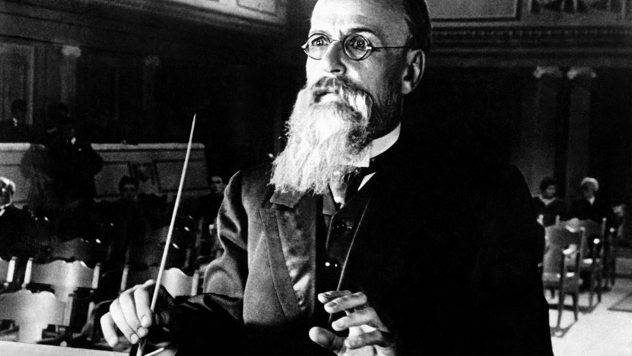 Ein älterer Mann mit langem Vollbart und Brille hält die Hände zum Dirigat bereit. Ein älterer Mann mit langem Vollbart und Brille hält die Hände zum Dirigat bereit.