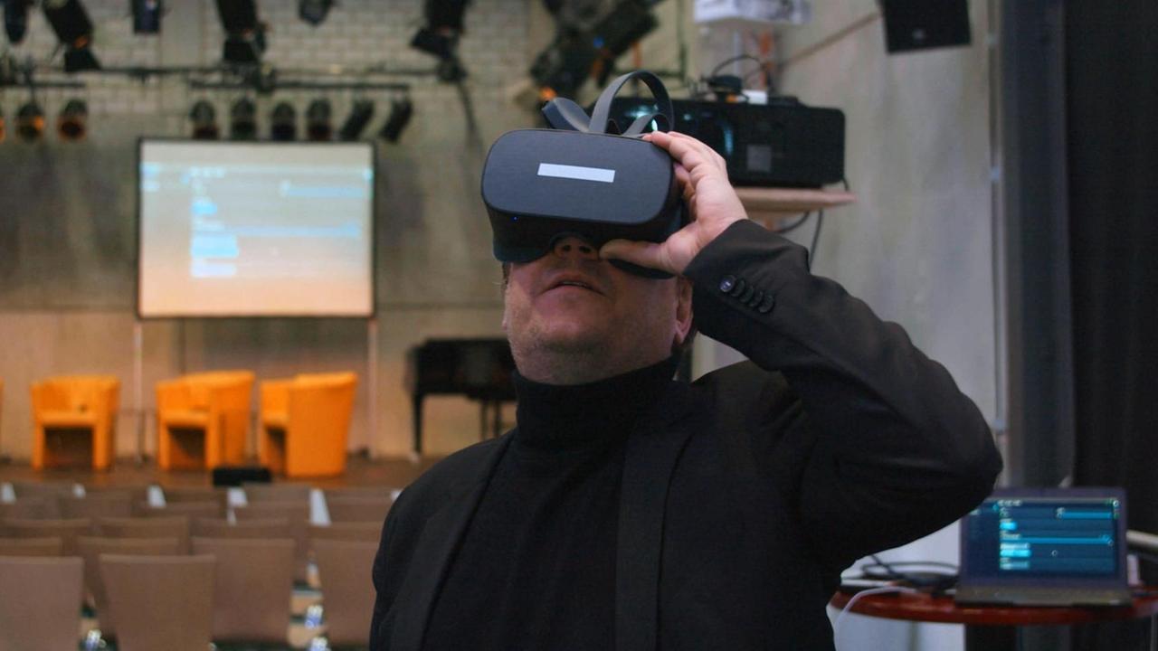 Ein Mann mit VR-Brille schaut sich in einem Theater um. Ein Mann mit VR-Brille schaut sich in einem Theater um.