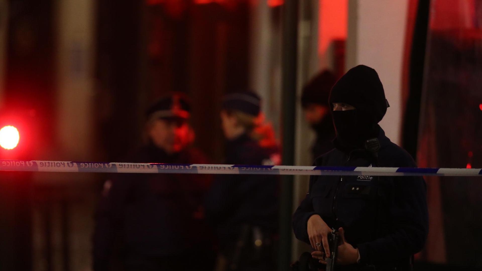 Ein maskierter Polizist hinter einem Absperrband Ein maskierter Polizist hinter einem Absperrband