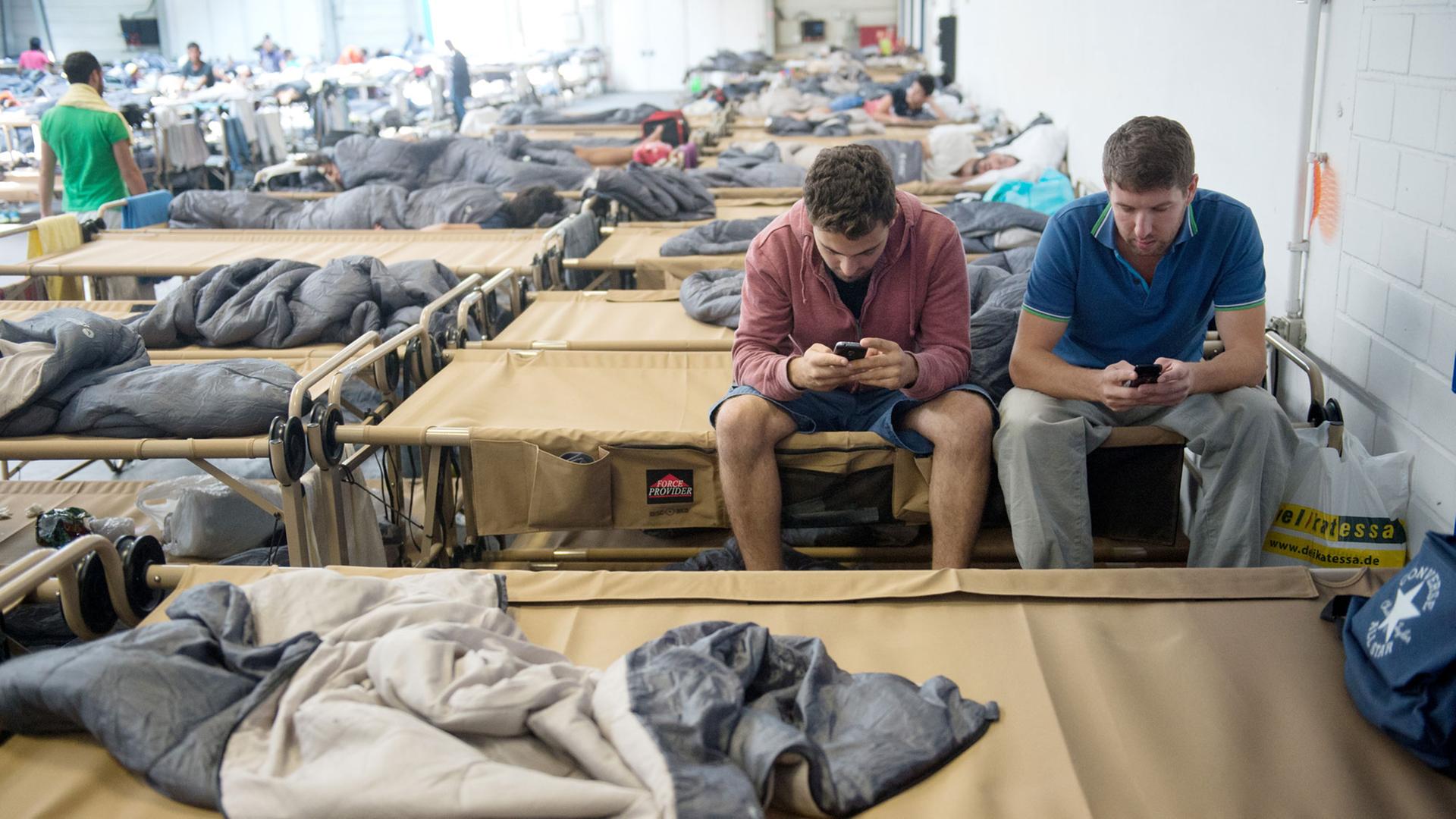 Zwei Flüchtlinge in einer Notunterkunft in Stuttgart mit ihren Smartphones Zwei Flüchtlinge in einer Notunterkunft in Stuttgart mit ihren Smartphones