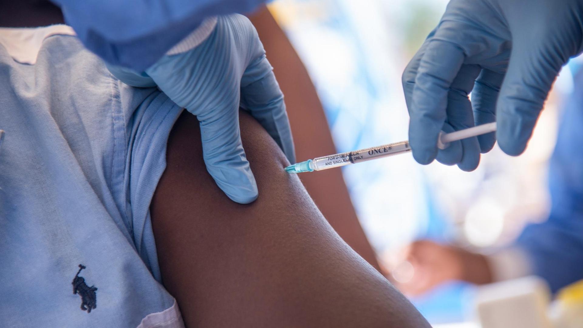 Eine Mitarbeiterin der Weltgesundheitsorganisation WHO spritzt eine Impfung in den Oberarm eines Patienten im kongolesischen Ort Mbandaka