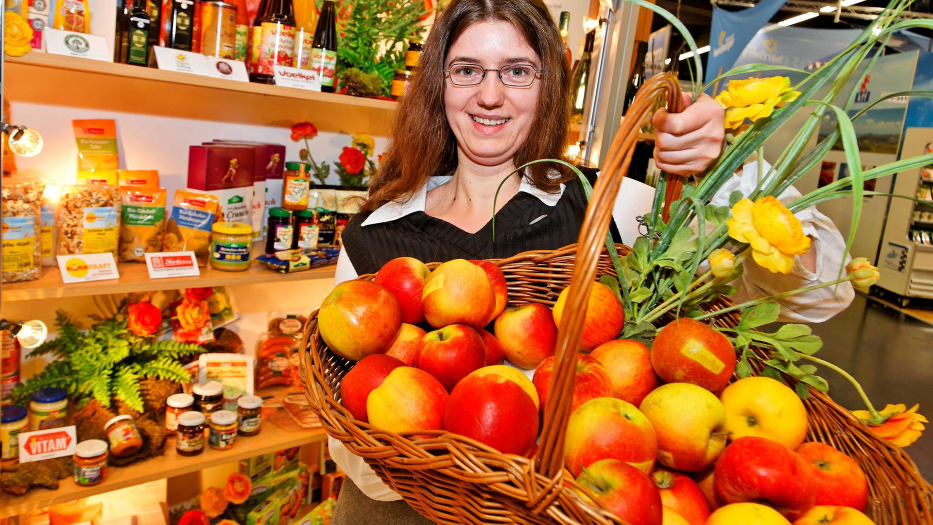 Messehostess präsentiert Bioprodukte an einem Messestand auf der "Biofach" - einer Messe für Bioprodukte Messehostess präsentiert Bioprodukte an einem Messestand auf der "Biofach" - einer Messe für Bioprodukte