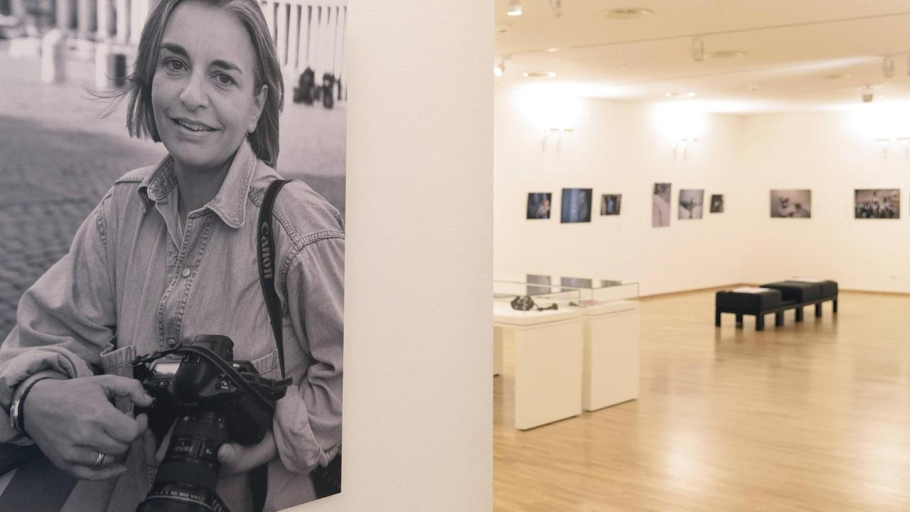 Blick in die Ausstellung. Im Vordergrund ein großformatiges Portrait der Fotografin, im Hintergrund Vitrinen und Bilder an den Wänden. Blick in die Ausstellung. Im Vordergrund ein großformatiges Portrait der Fotografin, im Hintergrund Vitrinen und Bilder an den Wänden.