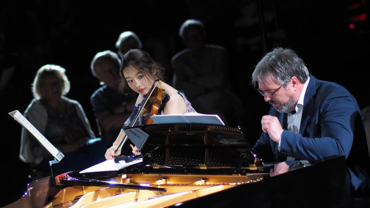Eine Geigerin wendet sich dem Pianisten zu, der gemeinsam mit ihr spielt. Eine Geigerin wendet sich dem Pianisten zu, der gemeinsam mit ihr spielt.