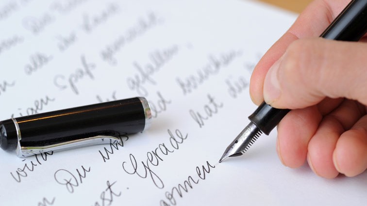 Die Hand einer Frau, die einen Brief mit einem Füllfederhalter schreibt. Die Hand einer Frau, die einen Brief mit einem Füllfederhalter schreibt.