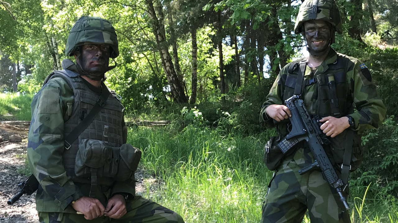 Soldaten der schwedischen Armee in braun-grünen Tarnanzügen, Maschinengewehre vor den Bäuchen und unter den Helmen geschwärzte Gesichter Soldaten der schwedischen Armee in braun-grünen Tarnanzügen, Maschinengewehre vor den Bäuchen und unter den Helmen geschwärzte Gesichter