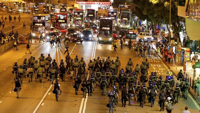 Polizisten kommen an der Causeway Bay an, wo Demonstranten mit Barrikaden den Straßenverkehr behindern.