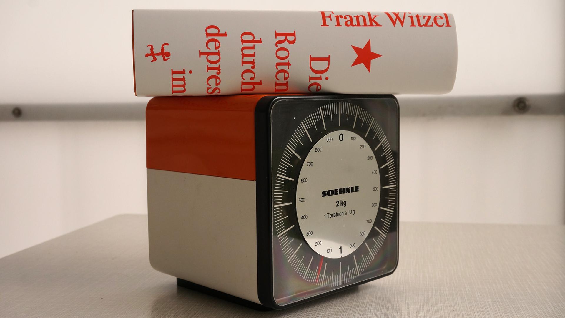 Der Roman "Die Erfindung der Roten Armee Fraktion durch einen manisch-depressiven Teenager im Sommer 1969" von Frank Witzel liegt auf einer Küchenwaage, die etwa 1100 Gramm anzeigt. Der Roman "Die Erfindung der Roten Armee Fraktion durch einen manisch-depressiven Teenager im Sommer 1969" von Frank Witzel liegt auf einer Küchenwaage, die etwa 1100 Gramm anzeigt.