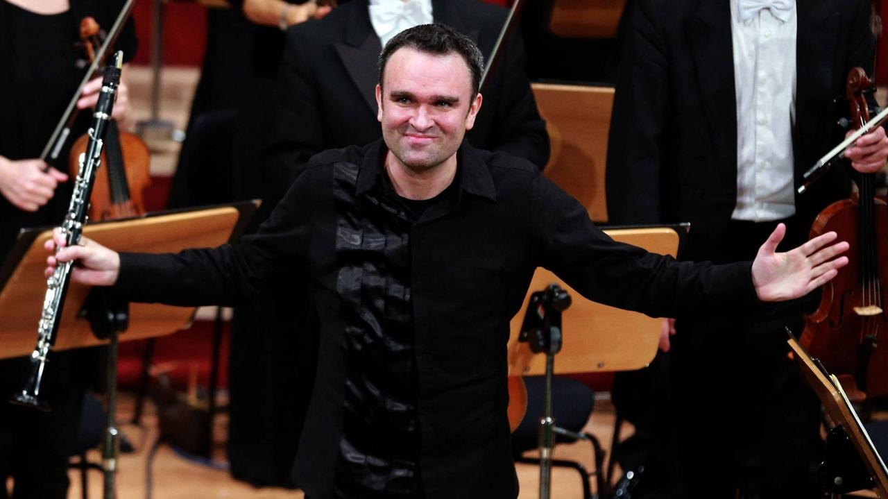 Der Klarinettist Jörg Widmann steht beim Musikfestival Heidelberger Frühling im April 2016 auf der Bühne. In der rechten Hand hält er eine Klarinette und er bedankt sich beim Publikum. Der Klarinettist Jörg Widmann steht beim Musikfestival Heidelberger Frühling im April 2016 auf der Bühne. In der rechten Hand hält er eine Klarinette und er bedankt sich beim Publikum.