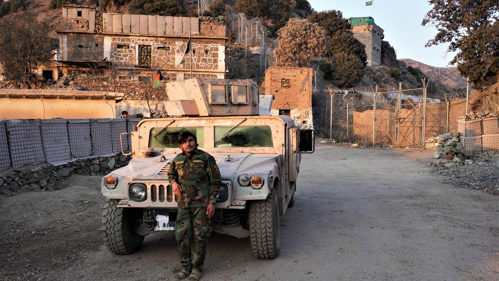 Ein Grenzposten in der afghanischen Provinz Kunar an der Grenze zu Pakistan. Er lehnt vor einem Militärfahrzeug. Hinter ist der Grenzzaun. Ein Grenzposten in der afghanischen Provinz Kunar an der Grenze zu Pakistan. Er lehnt vor einem Militärfahrzeug. Hinter ist der Grenzzaun.