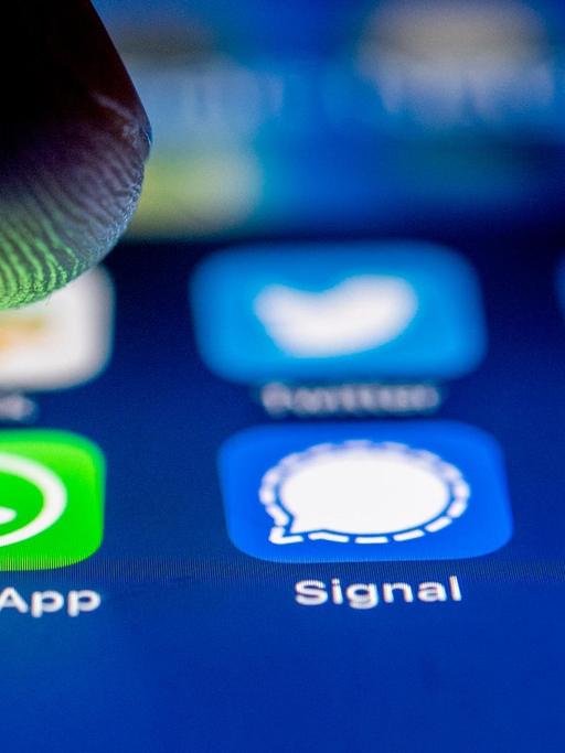Die App-Logos fuer die Messenger WhatsApp, Signal und Telegram auf einem iPhone Smartphone.