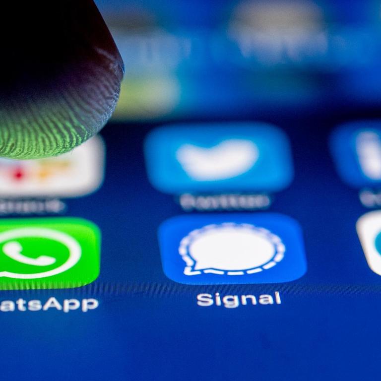 Die App-Logos fuer die Messenger WhatsApp, Signal und Telegram auf einem iPhone Smartphone.