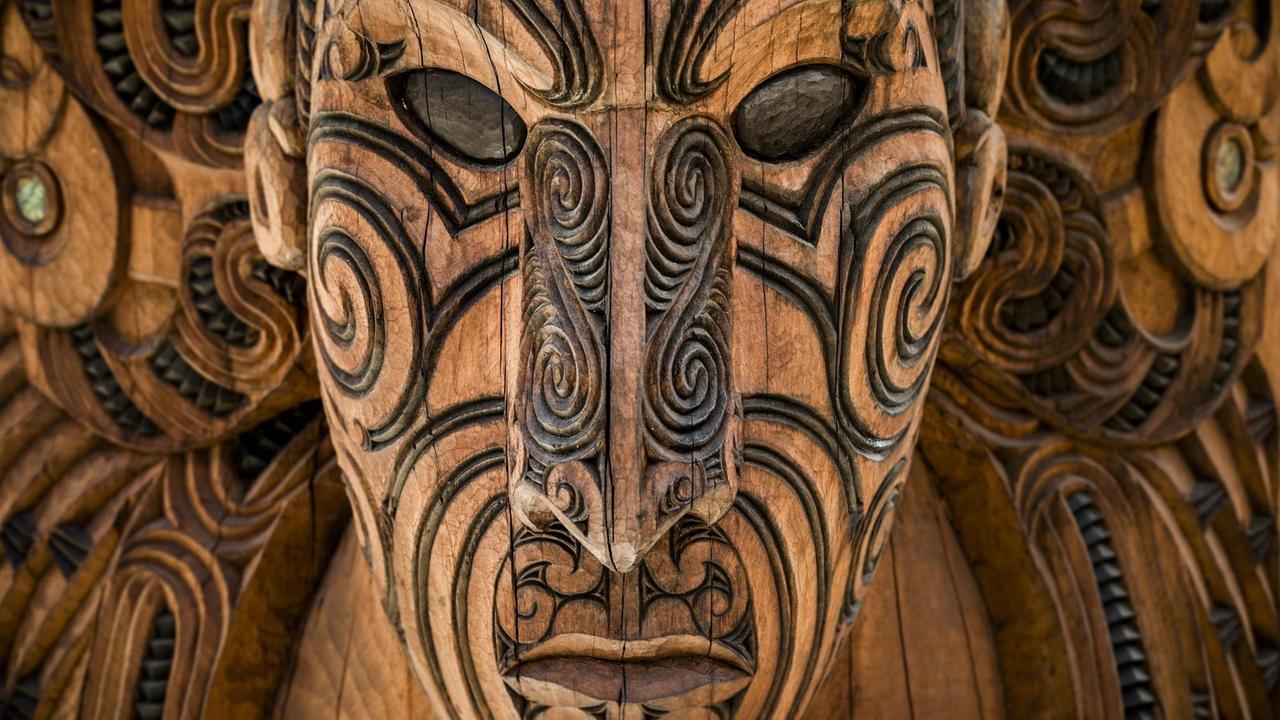 Eine geschnitzte Maske der Maori blickt dem Betrachter entgegen. Eine geschnitzte Maske der Maori blickt dem Betrachter entgegen.