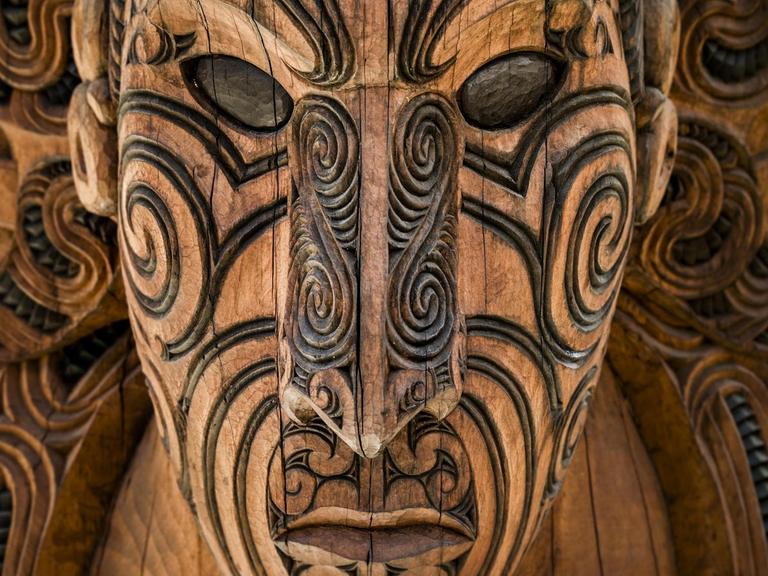 Eine geschnitzte Maske der Maori blickt dem Betrachter entgegen.