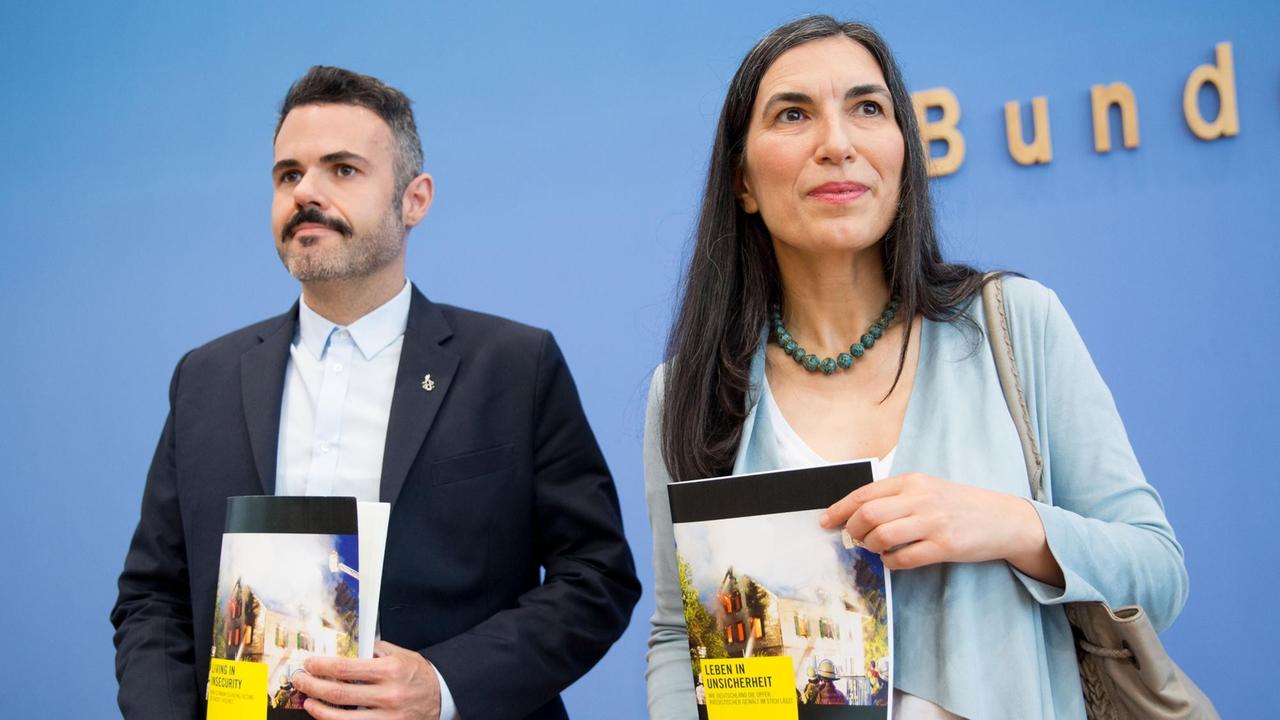 Selmin Caliskan und Marco Perolini halten den Bericht zu rassistischer Gewalt in Deutschland in die Kameras. Selmin Caliskan und Marco Perolini halten den Bericht zu rassistischer Gewalt in Deutschland in die Kameras.
