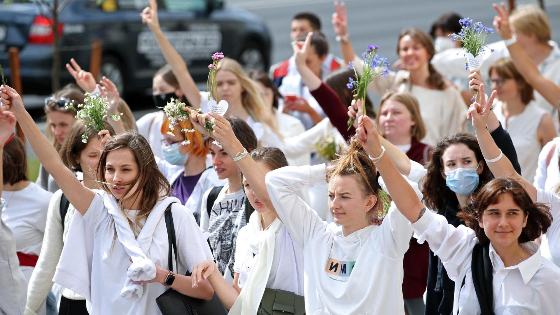 Junge Frauen demonstrieren. Sie tragen weiße Kleidung und halten Blumen in den Händen. Junge Frauen demonstrieren. Sie tragen weiße Kleidung und halten Blumen in den Händen.