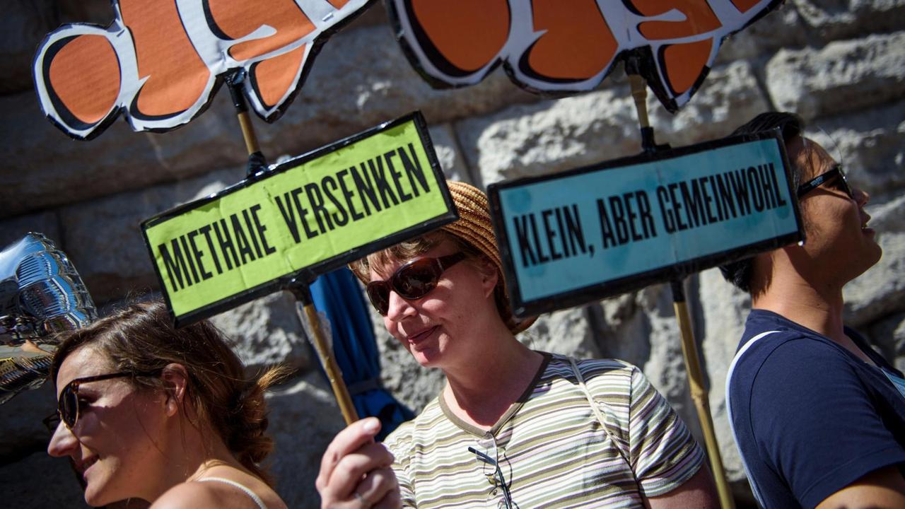 Eine Aktivistin der Initiative "Deutsche Wohnen & Co enteignen" nimmt mit selbstgebastelten Schildern, afu dem "Miethaie versenken" und "Klein, aber Gemeinwohl" steht, an der Übergabe von 77.001 Unterschriften zur Anstrebung eines Volksbegehrens an die Berliner Senatsverwaltung für Inneres und Sport teil. Eine Aktivistin der Initiative "Deutsche Wohnen & Co enteignen" nimmt mit selbstgebastelten Schildern, afu dem "Miethaie versenken" und "Klein, aber Gemeinwohl" steht, an der Übergabe von 77.001 Unterschriften zur Anstrebung eines Volksbegehrens an die Berliner Senatsverwaltung für Inneres und Sport teil.
