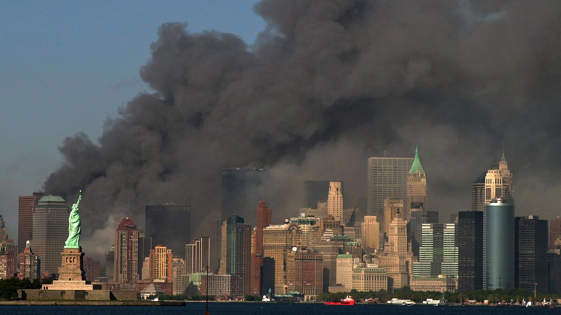 Am 11. September 2001 steigt dichter Rauch aus dem Bereich hinter der Freiheitsstatue (unten links) in den Himmel, wo die Türme des World Trade Centers standen. Am 11. September 2001 steigt dichter Rauch aus dem Bereich hinter der Freiheitsstatue (unten links) in den Himmel, wo die Türme des World Trade Centers standen.
