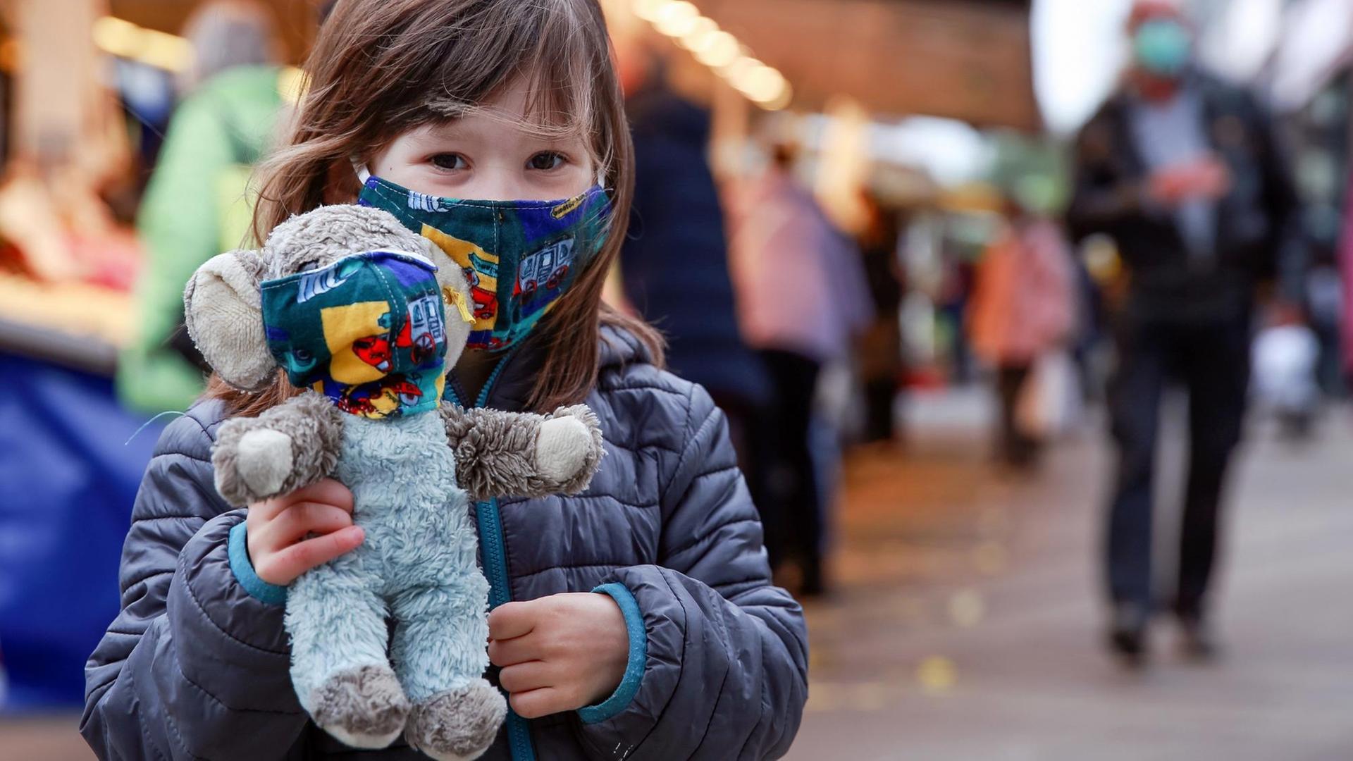 Ein Maedchen trägt auf einem Wochenmarkt in Hamburg einen selbstgenaehten Mundschutz