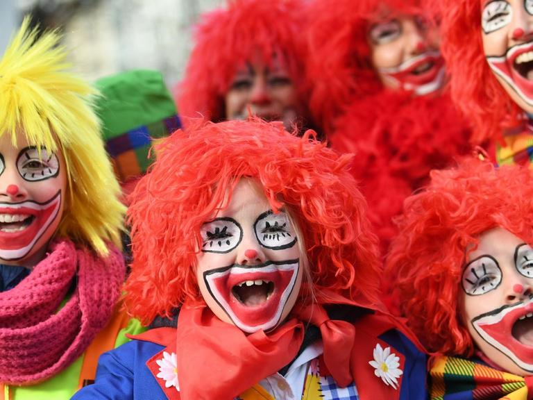 12.02.2018, Nordrhein-Westfalen, Düsseldorf: Als Clowns geschminkte Karnevalisten nehmen an dem Rosenmontagszug teil.