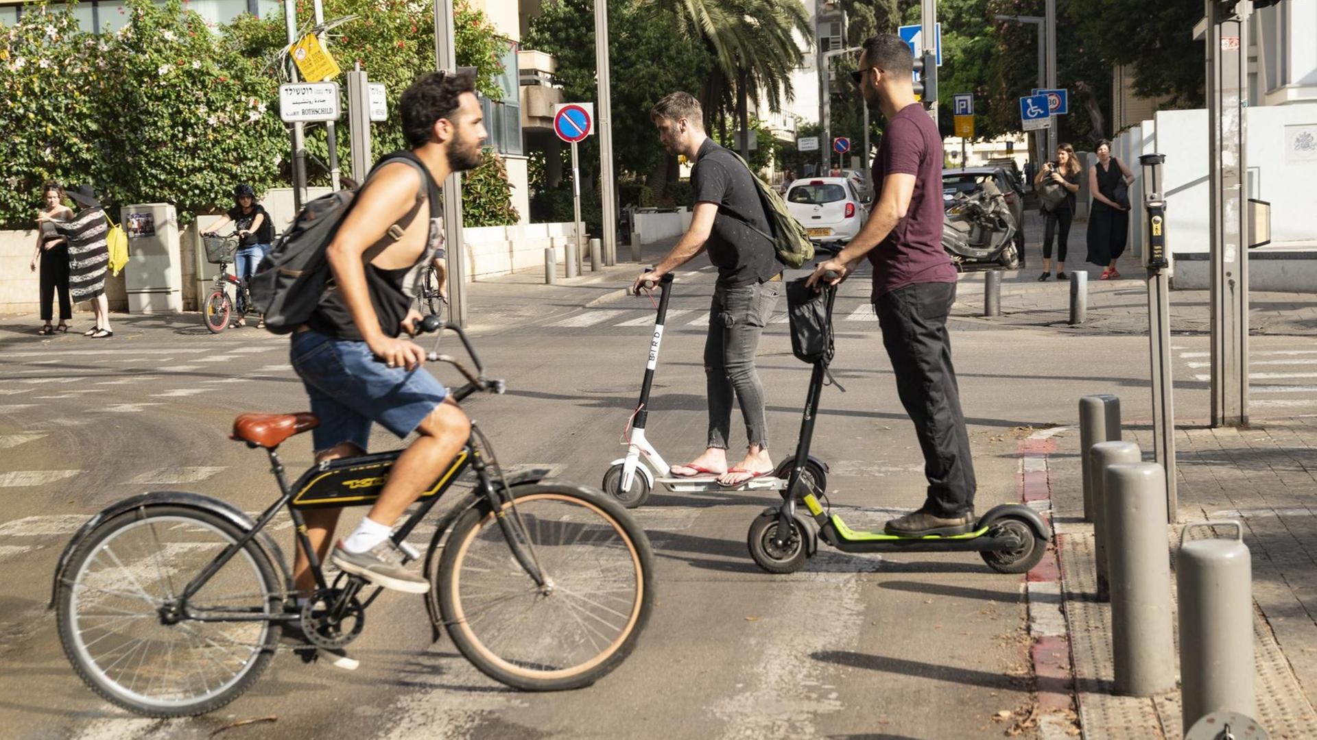 Fahrrad- und E-Rollerfahrer überqueren eine Straße in Tel Aviv. Fahrrad- und E-Rollerfahrer überqueren eine Straße in Tel Aviv.