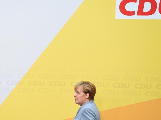 Bundeskanzlerin Angela Merkel (CDU) läuft am 25.09.2017 auf einer Bühne an einer Wand mit der Aufschrift "CDU" vorbei.