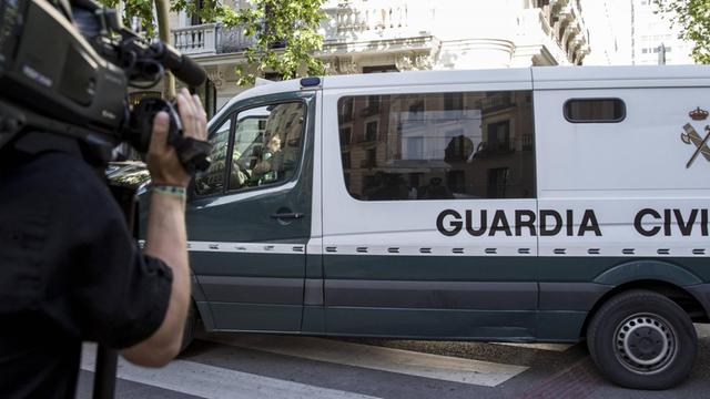 Eine Kamera filmt einen Gefangenentransport der spanischen Polizei.