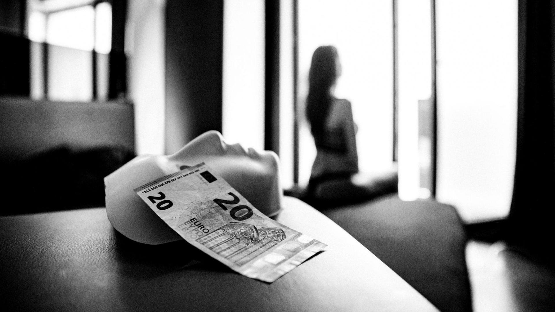 Eine weiße Maske und ein 20-Euro-Schein liegen auf einem Bett. Eine weiße Maske und ein 20-Euro-Schein liegen auf einem Bett.