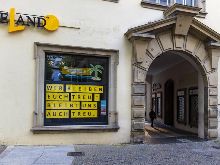 Am Fenster eines geschlossenen Reisebüros in Stuttgart steht: "Wir bleiben euch treu - bleibt uns auch treu".