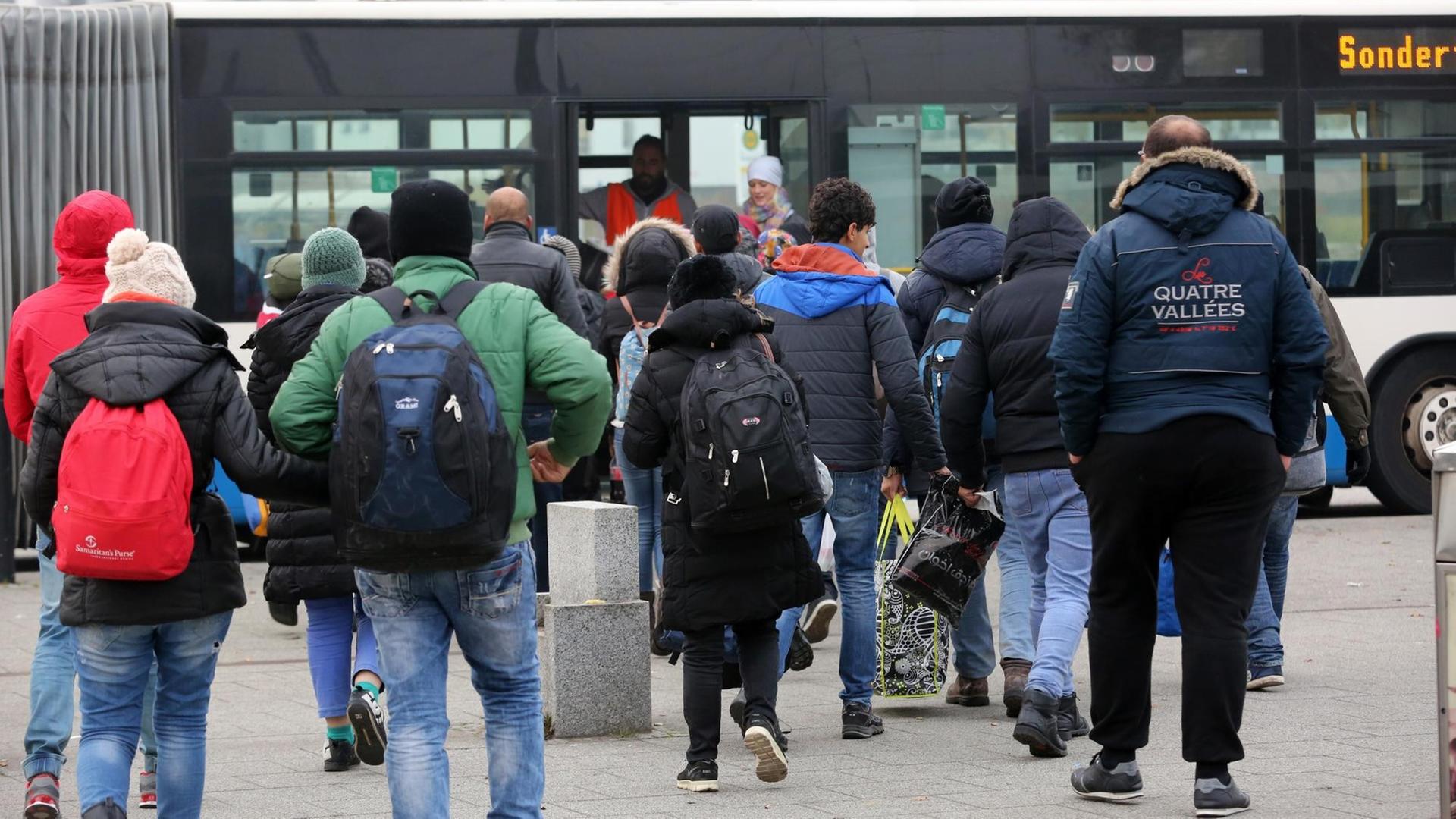 Ein Dutzend Flüchtlinge auf dem Weg zu einem Bus.
