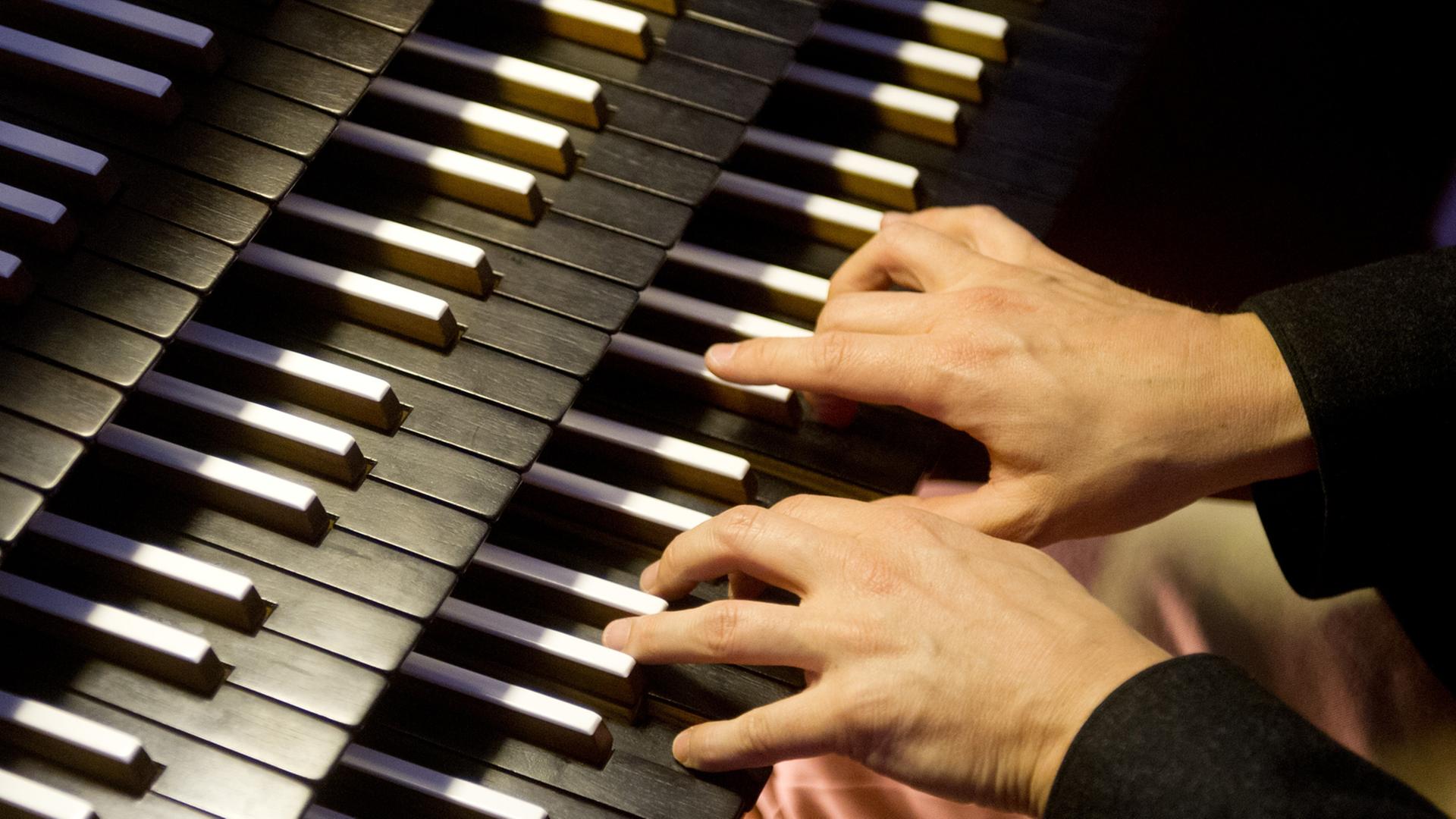 Ein Organist bedient in München in der katholischen Kirche St. Sylvester beim Spielen die Tasten der Orgel.