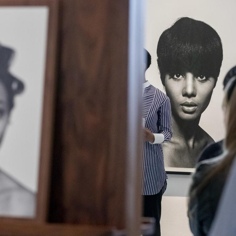 Eine Fotografie von Moneta Sleet Jr. (r.) ist in der Ausstellung "The Black Image Corporation" im Martin-Gropius-Bau hinter Besuchern einer Pressekonferenz zu sehen. 