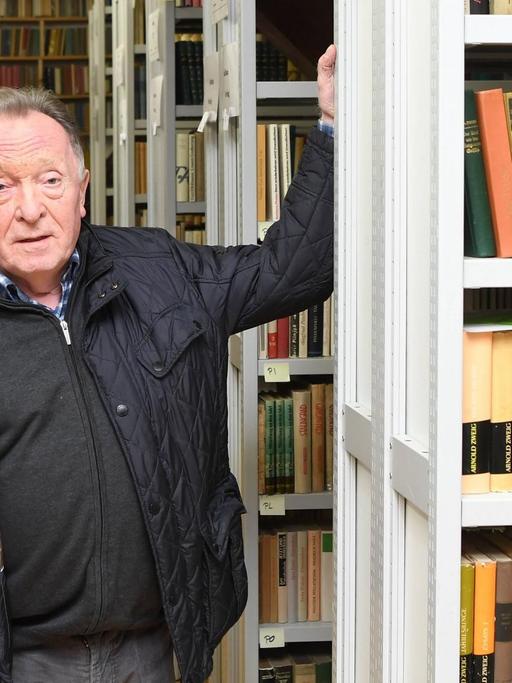 Peter Sodann steht inmitten von Buchregalen seiner Sammlung von Büchern, die in der DDR erschienen sind.