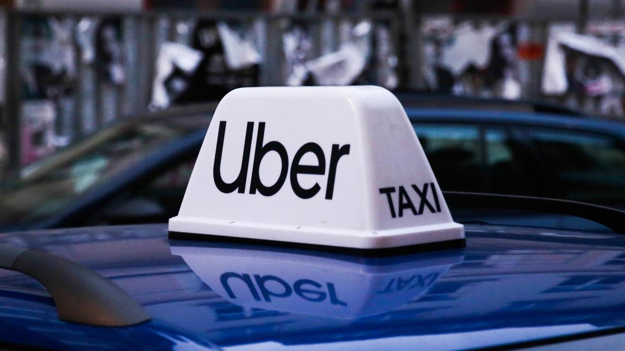 Ein Auto trägt auf dem Dach ein Uber Zeichen, an dem auf der Seite "Taxi" zu lesen ist. Ein Auto trägt auf dem Dach ein Uber Zeichen, an dem auf der Seite "Taxi" zu lesen ist.