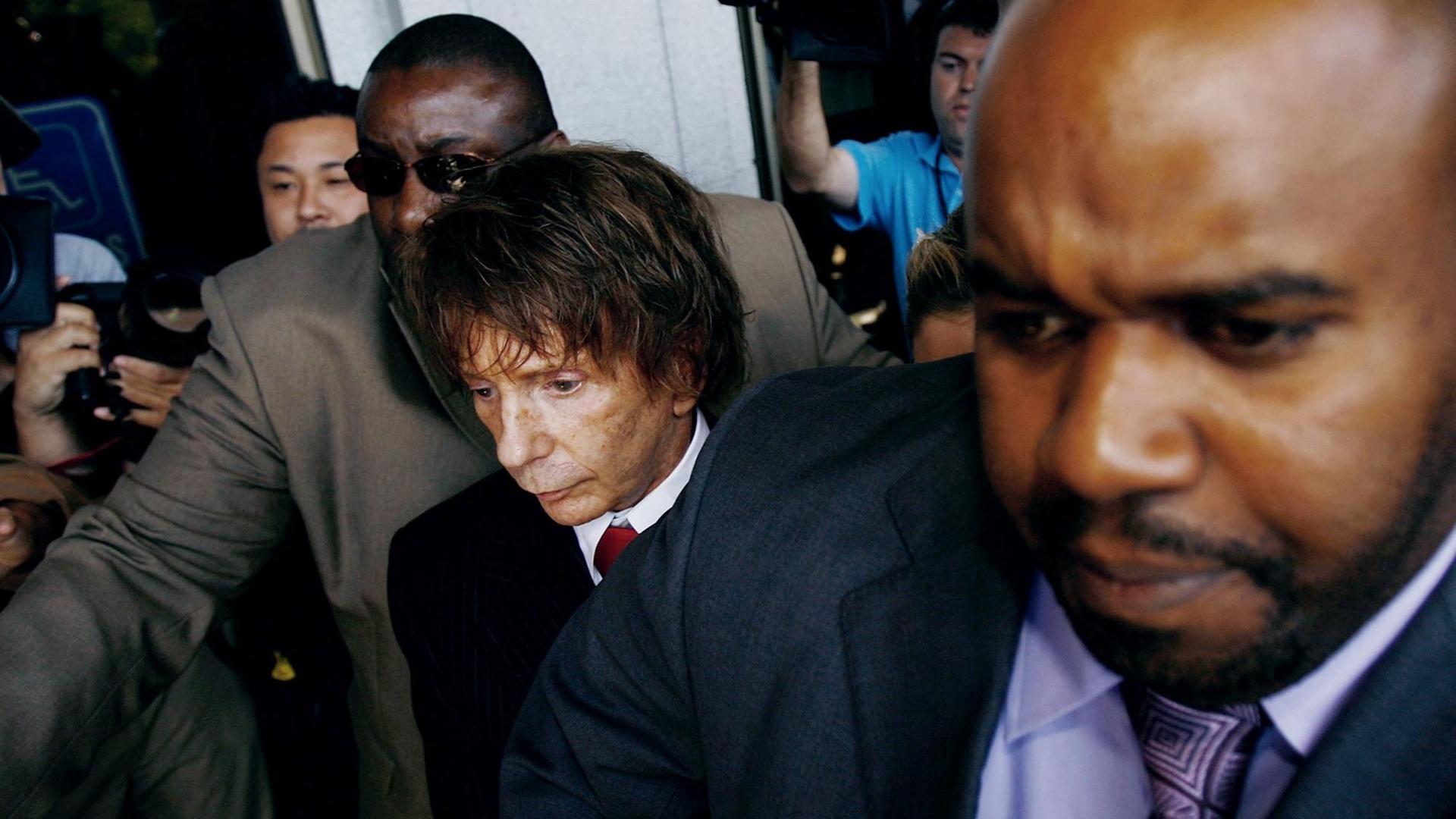 Phil Spector umringt von Bodyguards beim Verlassen eines Gerichtssaals. Phil Spector umringt von Bodyguards beim Verlassen eines Gerichtssaals.