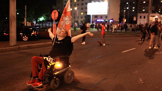 Ein Demonstrant im Rollstuhl ist mit vielen anderen Protestierenden auf der Straße.