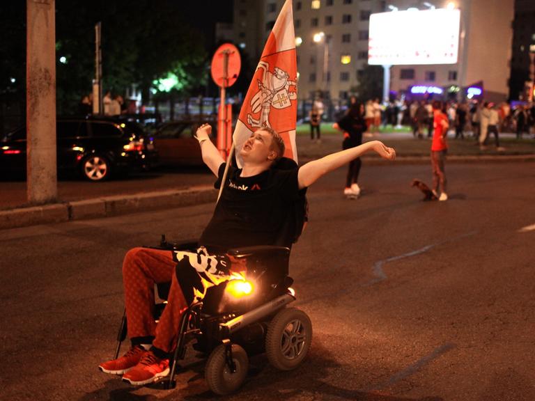 Ein Demonstrant im Rollstuhl ist mit vielen anderen Protestierenden auf der Straße.
