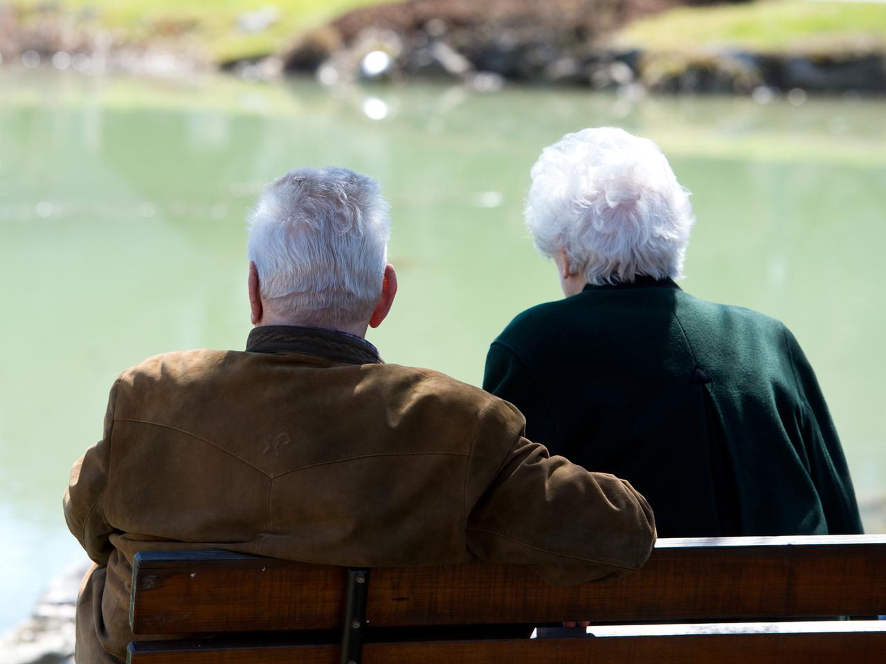 Zwei Senioren sitzen an einem kleinen Teich. Zwei Senioren sitzen an einem kleinen Teich.