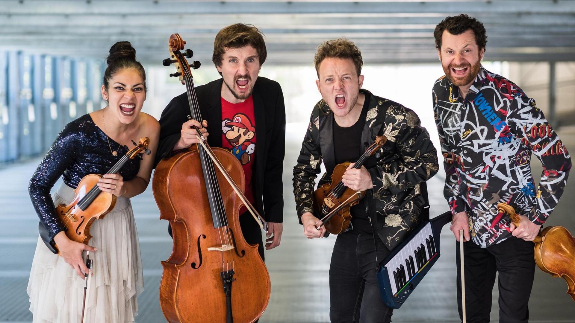 Die vier Musiker stehen mit ihren Instrumenten unterm Arm laut Brüllend in einer Tiefgarage Die vier Musiker stehen mit ihren Instrumenten unterm Arm laut Brüllend in einer Tiefgarage