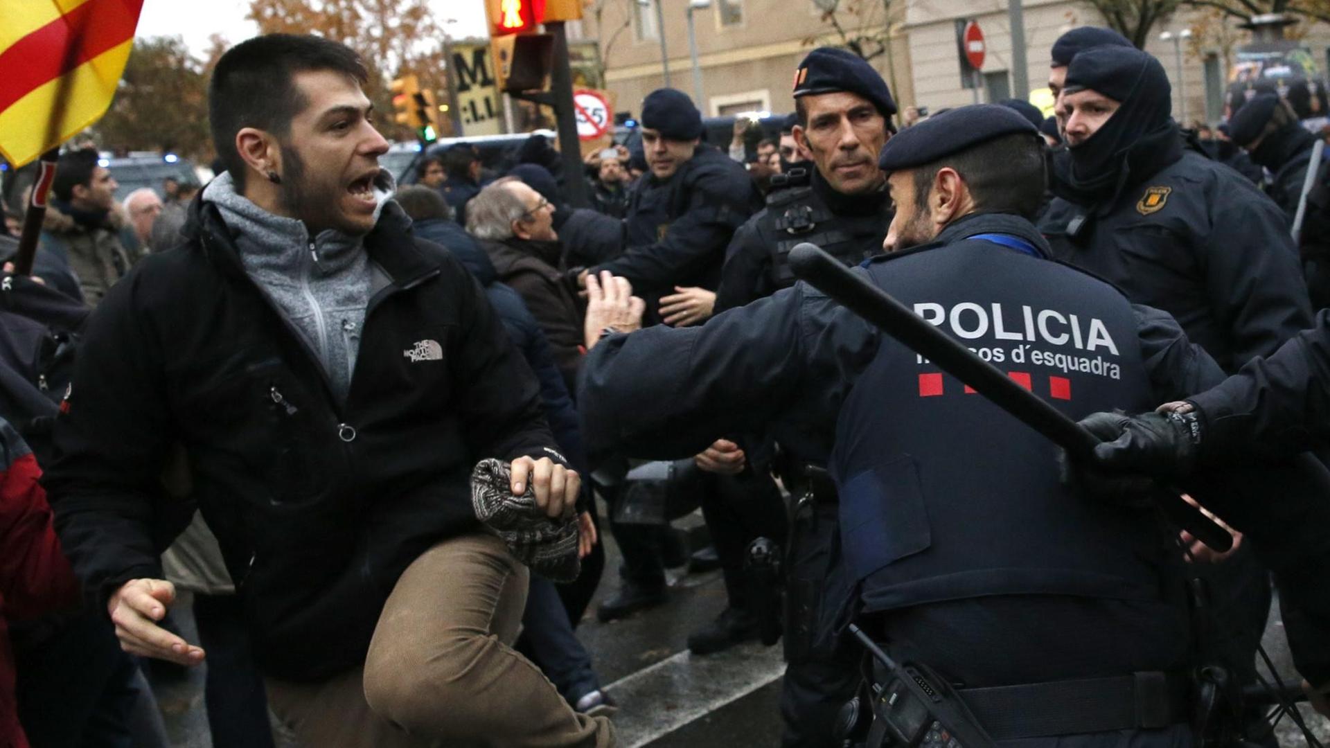 Polizisten der katalanischen Einheit Mossos d'Esquadra halten am 11.12.2017 vor dem Diözesanmuseum der Stadt Lleida in Katalonien (Spanien) wütende Demonstranten zurück.