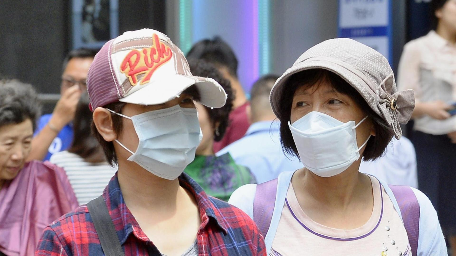 Koreaner mit Atem-Schutzmasken in einer Einkaufsgegend von Seoul Koreaner mit Atem-Schutzmasken in einer Einkaufsgegend von Seoul