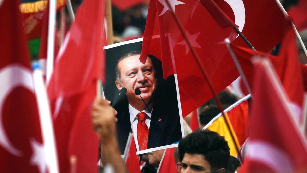 Anhänger des türkischen Staatspräsidenten Recep Tayyip Erdogan halten in Köln Fahnen und ein Bild des Staatschefs. Anhänger des türkischen Staatspräsidenten Recep Tayyip Erdogan halten in Köln Fahnen und ein Bild des Staatschefs.