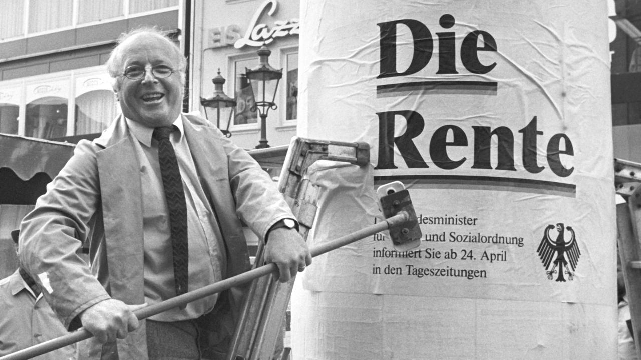 Eigenhändig greift Bundesarbeitsminister Norbert Blüm am 21.4.1986 auf dem Marktplatz in Bonn zum Leimpinsel, um das erste Plakat einer Informations-Aktion zur Sicherheit der Renten auf eine Litfaßsäule zu kleben. Der Text des Plakates lautet:"... denn eins ist sicher: Die Rente".