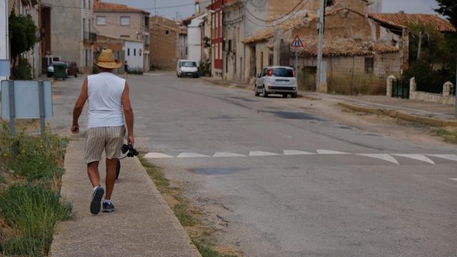 Spanien, die Gemeinde Caminreal östlich von Madrid: Ein Mann spaziert mit seinem Hund eine Straße entlang.