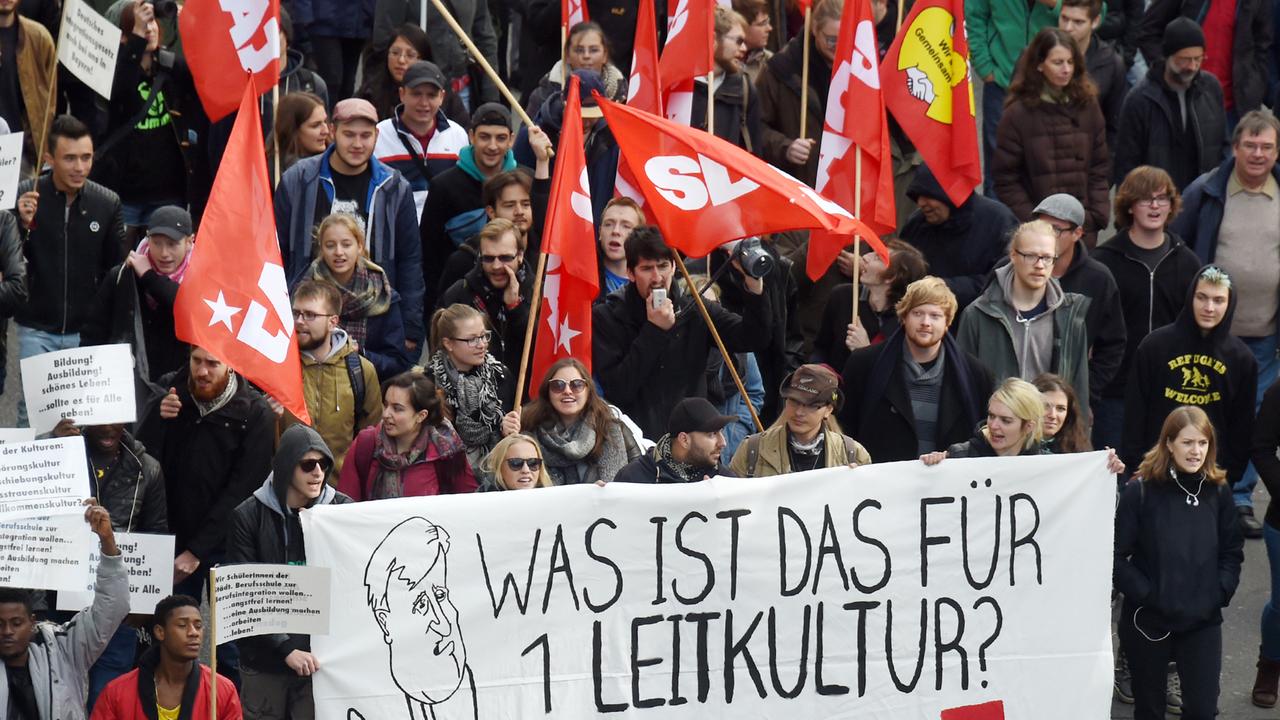 Demonstranten tragen ein Transparent mit der Aufschrift "Was ist das für 1 Leitkultur?". Demonstranten tragen ein Transparent mit der Aufschrift "Was ist das für 1 Leitkultur?".