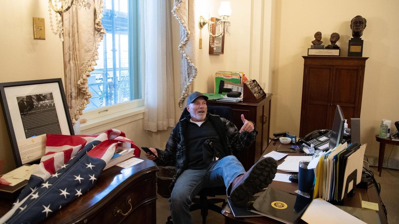 Ein Trump-Anhänger hat sich im Büro von Nancy Pelosi breitgemacht und seinen Fuß auf den Schreibtisch abgelegt. Ein Trump-Anhänger hat sich im Büro von Nancy Pelosi breitgemacht und seinen Fuß auf den Schreibtisch abgelegt.