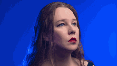 Porträt der Sängerin mit dunklen, langen, offenen Haaren vor blauem Hintergrund.